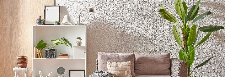 Zeitlos eingerichtetes Wohnzimmer vor Wand in Betonoptik.